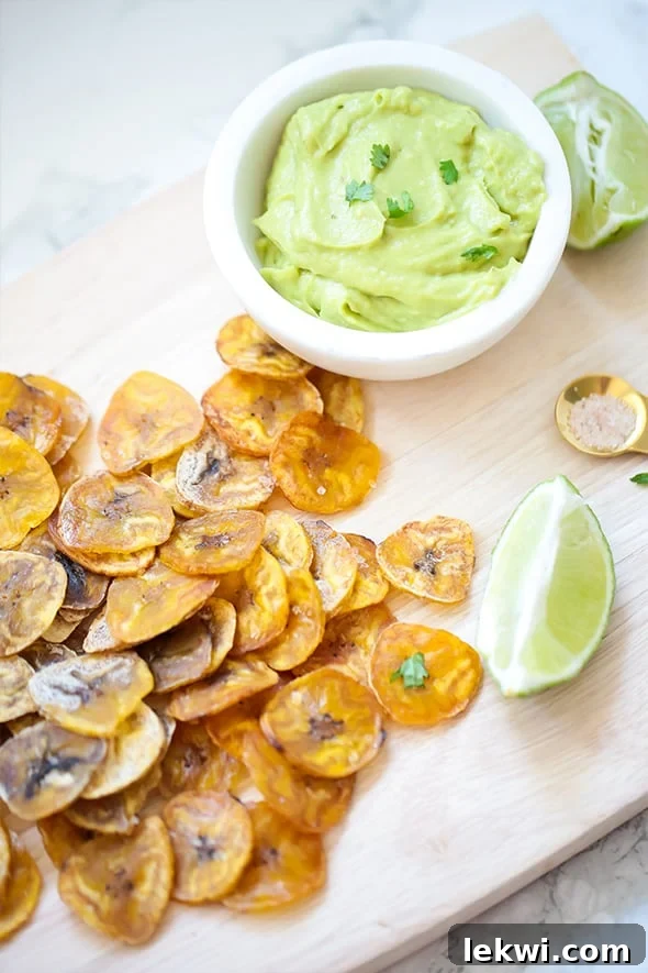 A close-up of a bowl overflowing with homemade baked plantain chips, showcasing their golden color and crisp texture.