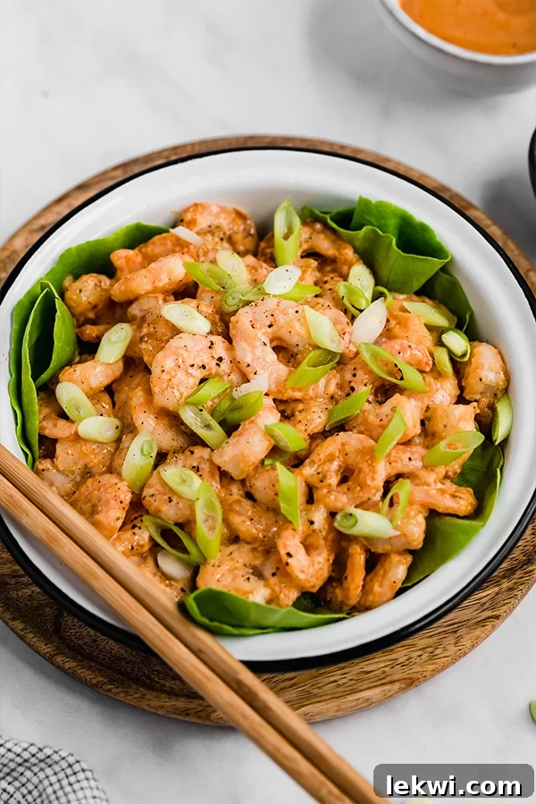 A vibrant bowl of crispy Bang Bang Shrimp, perfectly coated in a creamy sauce and garnished with fresh green onions, ready to be enjoyed.