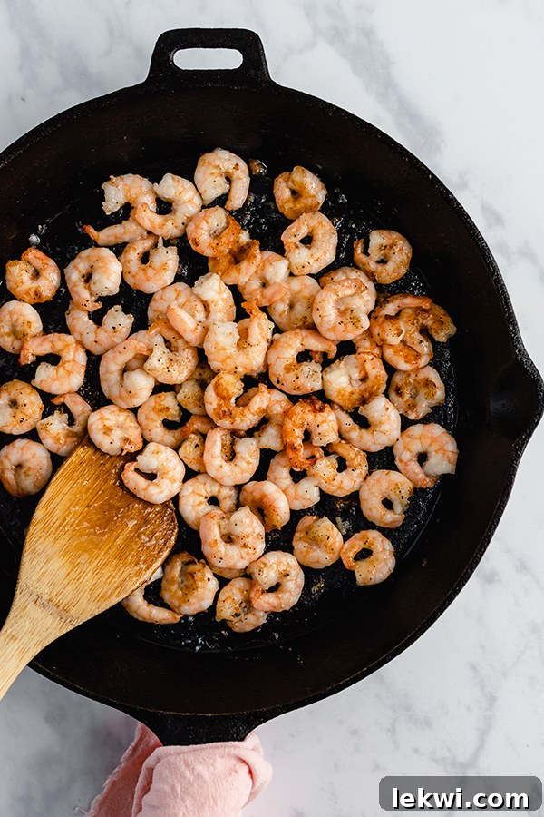 Bang Bang Shrimp being cooked in a skillet, showcasing the cooking process and golden brown color before being fully coated in sauce.