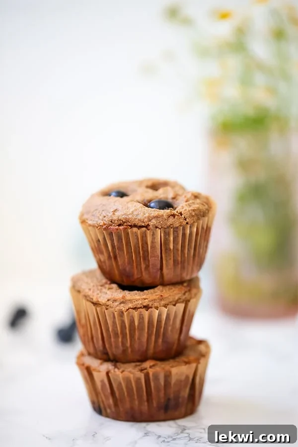 A beautifully arranged stack of freshly baked blueberry banana muffins, showcasing their golden-brown tops and inviting texture, ready to be enjoyed as a healthy, protein-rich treat.