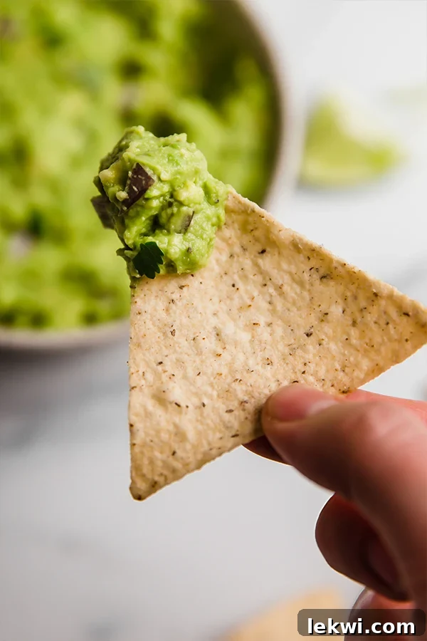A close-up shot of a plantain chip scooping a generous dollop of AIP Guacamole.