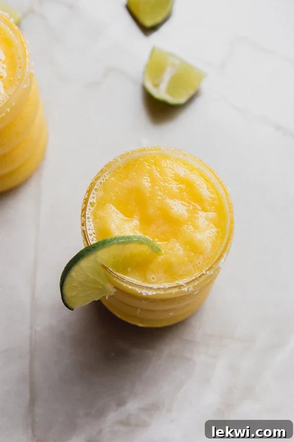 Lime slice on a glass of frozen mango margarita mocktail with a salt rim.
