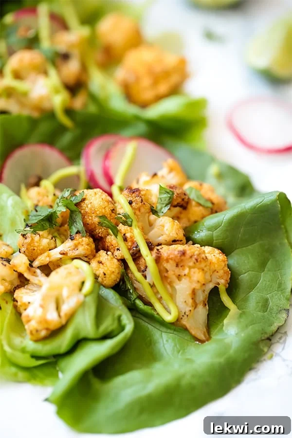 A close up of a bang bang cauliflower taco with lettuce on a counter with a slice of radish nearby.