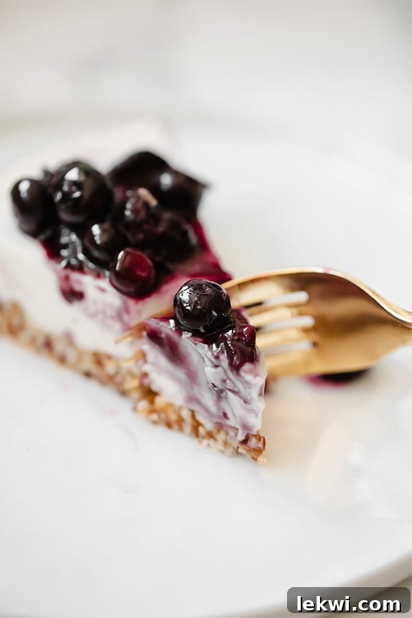 A close-up shot of a fork cutting into a creamy slice of blueberry lavender cheesecake, showing the delicate layers and vibrant purple hue of the filling.