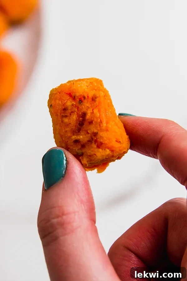 A single, perfectly baked sweet potato tater tot, showing its golden-brown exterior.