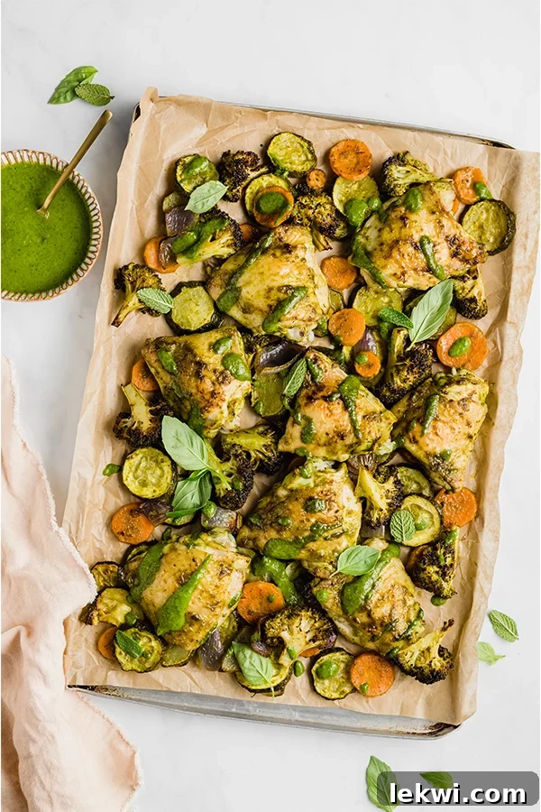 Chicken pesto with vegetables on a lined baking dish.