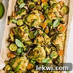 Chicken pesto with vegetables on a lined sheet pan.