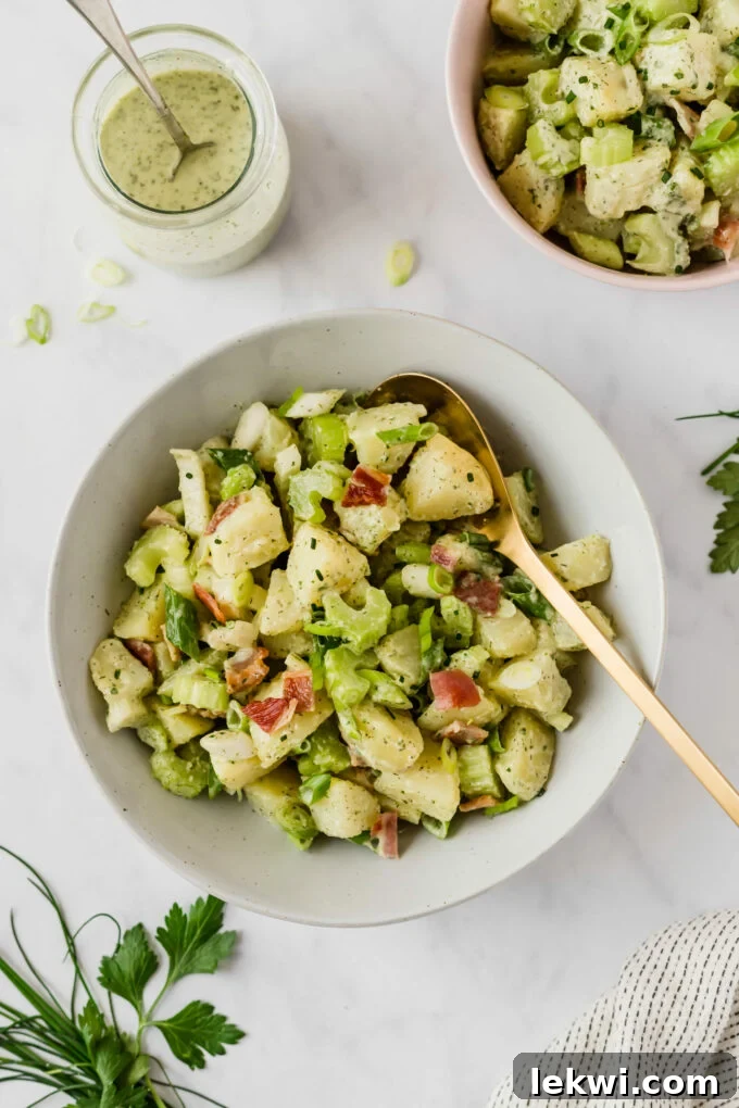 A white bowl filled with bacon ranch sweet potato salad and a serving spoon lying on it.