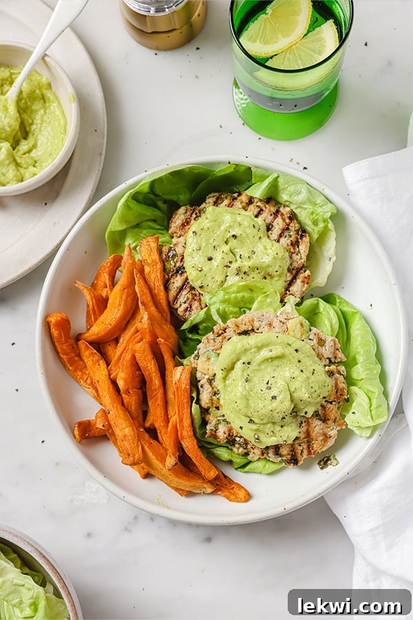 Delicious Spinach Avocado Chicken Burgers served on a plate with crispy sweet potato fries on the side, highlighting their vibrant green color and savory appeal.