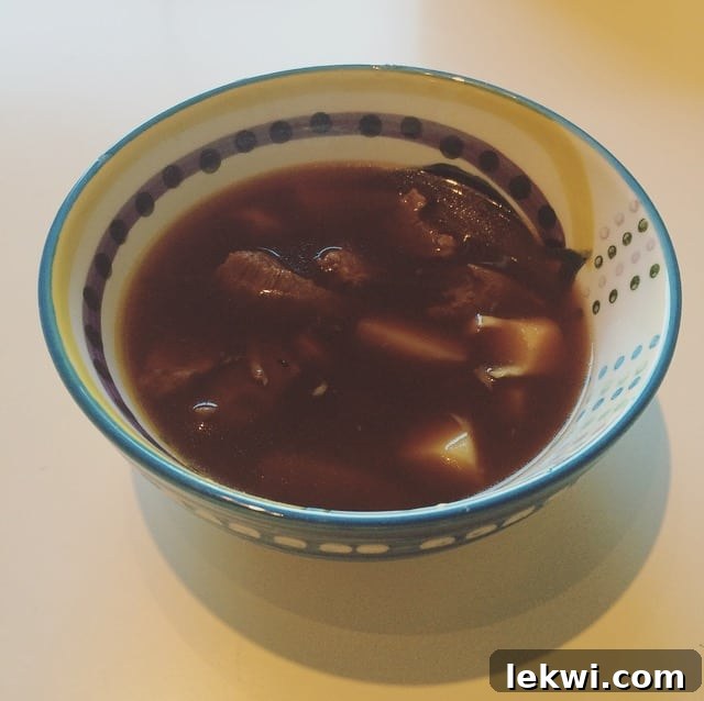 A close-up of a comforting bowl of homemade bone broth stew with meat and parsnips, signifying a nourishing and healing dinner.