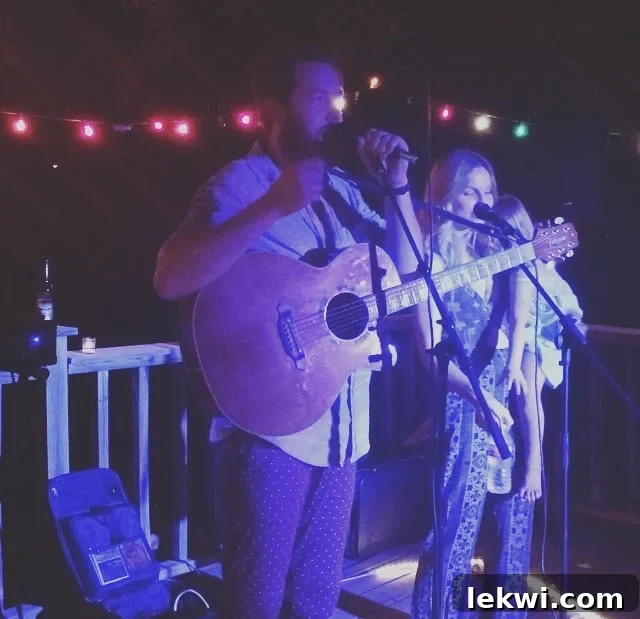 The musical duo Pilgrim, Katie and Aaron, performing live at a house concert, with instruments and a warm ambiance.