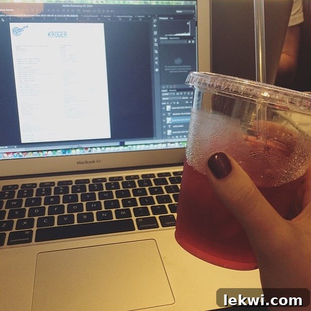 A cup of vibrant hibiscus tea next to a laptop, symbolizing a refreshing break during a productive work session on passion projects.