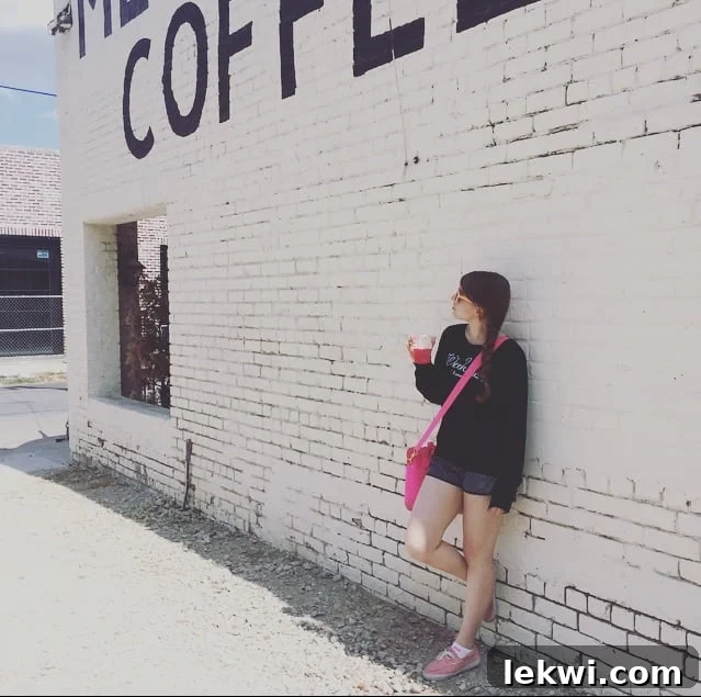 The author posing in a stylish Wildfox jumper outdoors, humorously battling the 100-degree Fahrenheit heat, eager for fall weather.