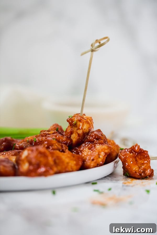 Platter of golden-brown Paleo BBQ Chicken Poppers garnished with fresh chives, ready for serving
