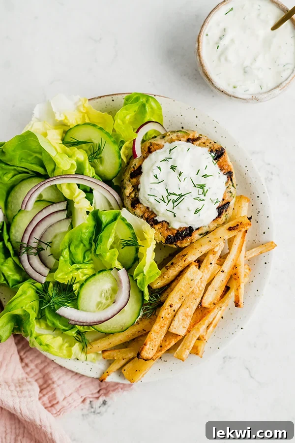Grilled greek chicken burger with toppings and fries on a plate