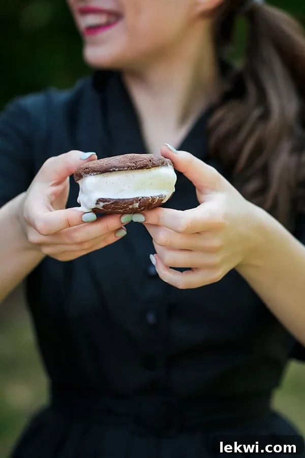 A person presenting a perfectly crafted homemade chocolate cookie ice cream sandwich, showcasing its delicious appeal.