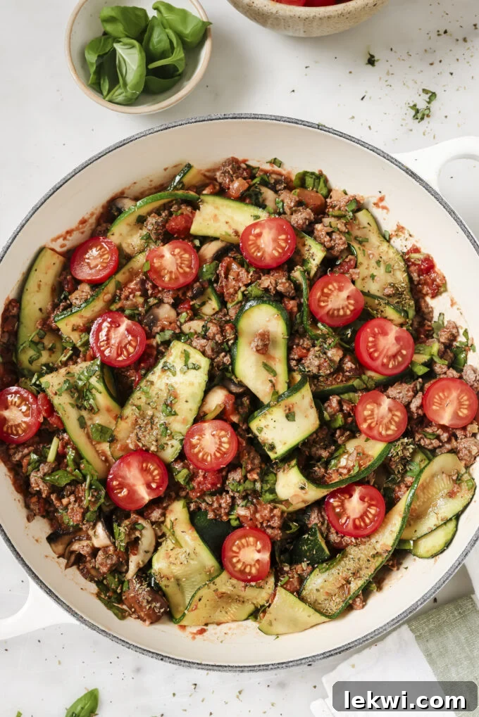 Zucchini lasagna skillet in a large white enamel pan with fresh tomatoes.