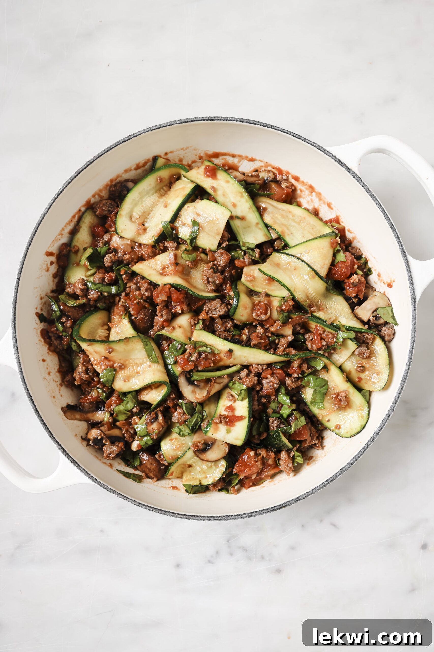Zucchini lasagna skillet in a large white enamel pan, with uncooked zucchini ribbons