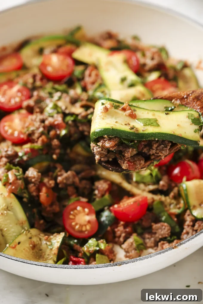 Spoon scooping lasagna skillet from a pan.