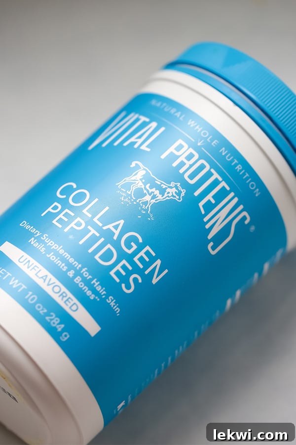 A canister of Vital Protein collagen peptides laying on a grey background, emphasizing the key ingredient.