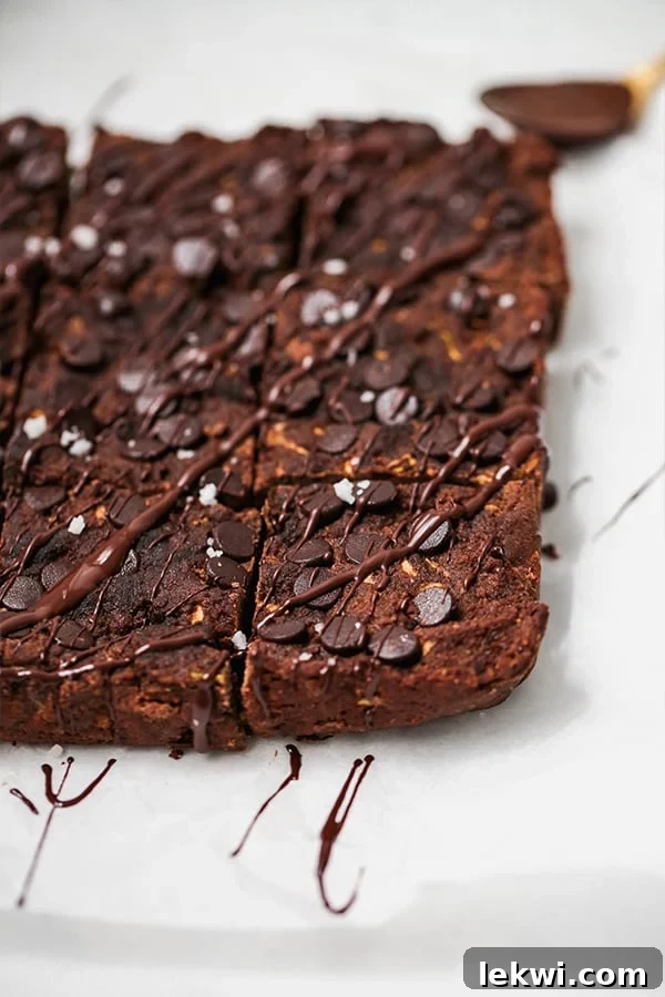 A pan of zucchini brownies cut into squares and sitting on a white counter.