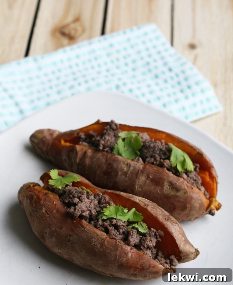 Close-up of a single, perfectly roasted sweet potato stuffed with seasoned ground bison and fresh herbs, showcasing a healthy and satisfying AIP meal.