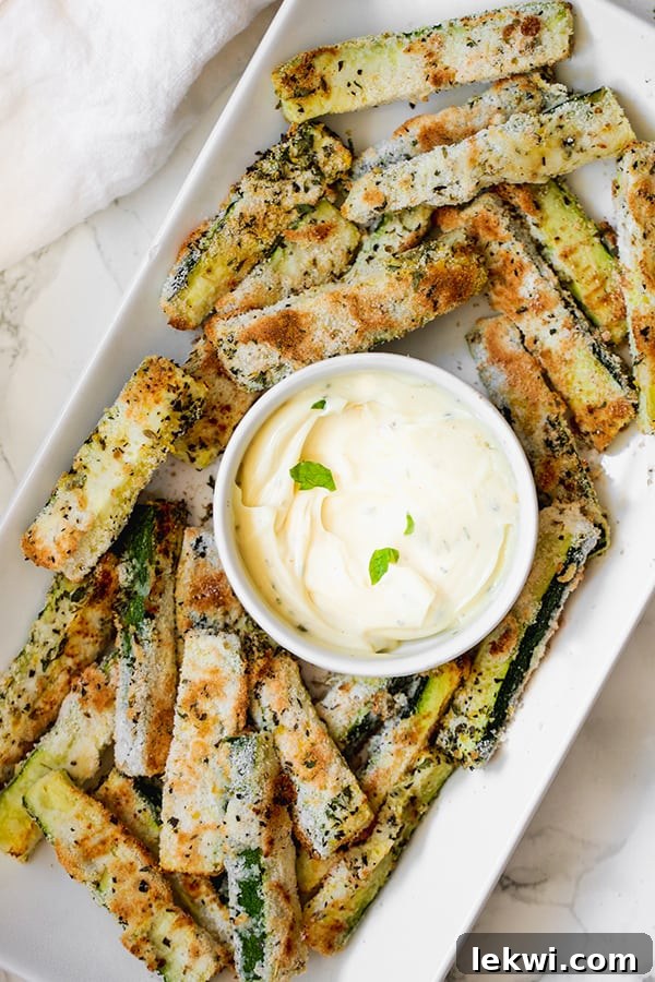 Crispy Baked Low Carb Zucchini Fries served with a creamy dipping sauce, perfect for a healthy snack or side dish.