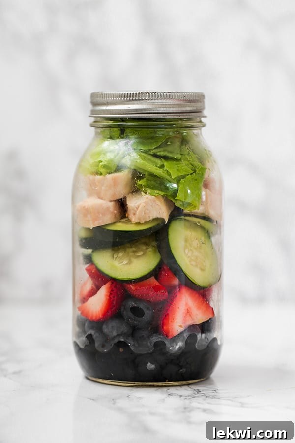 Mason jar berry chicken salad with balsamic dressing, berries, cucumber, chicken, and romaine