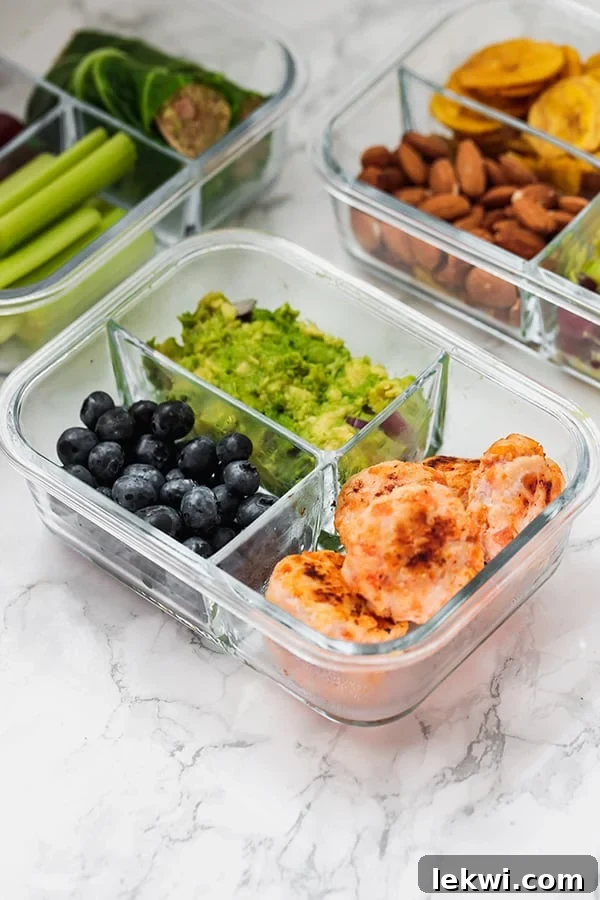 A glass meal prep container with chicken poppers, blueberries, and guacamole, symbolizing convenient paleo lunches.