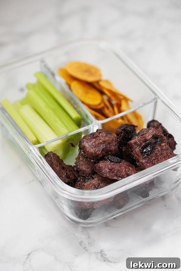 Cranberry beef jerky bites with celery sticks and plantain chips for a paleo snack box.