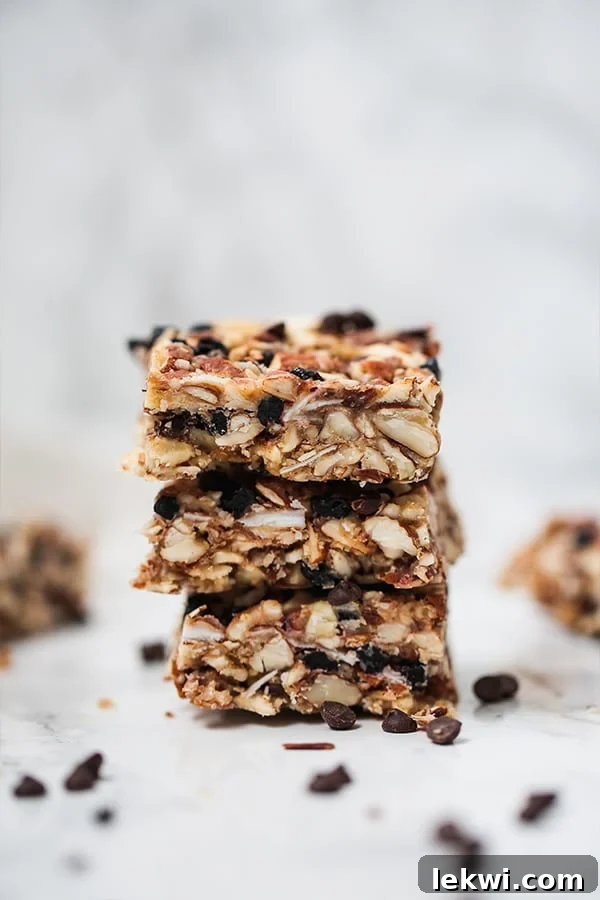 A close-up shot of three homemade Paleo Granola Bars stacked, revealing their rich, textured interior with visible nuts, coconut, and dried fruit.