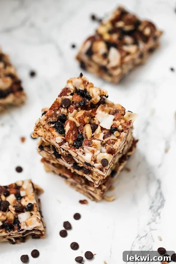 An overhead shot of several grain-free granola bar pieces scattered on a counter, with a few extra chocolate chips nearby, highlighting the bars' rustic appeal.