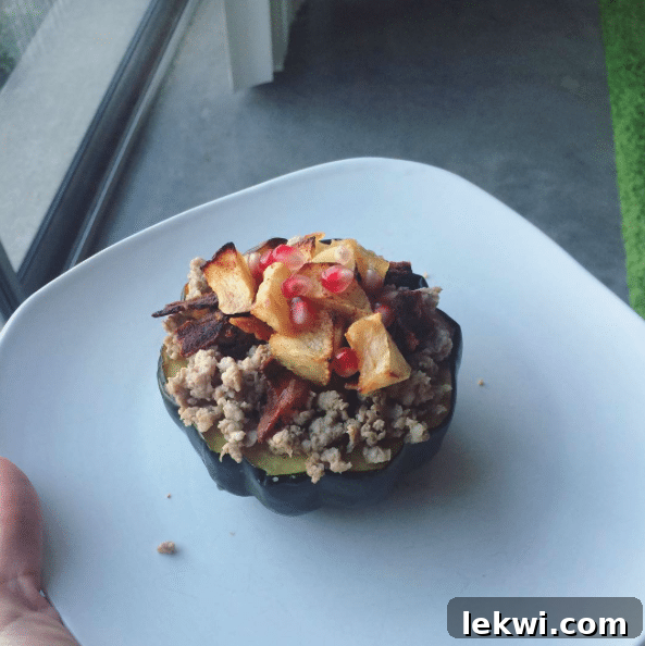 A rustic and wholesome stuffed acorn squash, filled with pastured pork, bacon, apples, and pomegranate seeds.