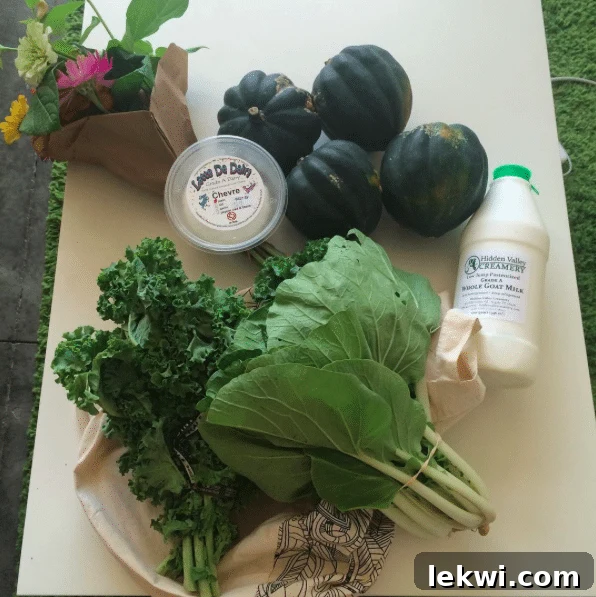 A bountiful haul from the farmers market, featuring fresh organic produce like acorn squash, kale, bok choy, and local goat dairy, alongside a vibrant bouquet of fresh flowers.
