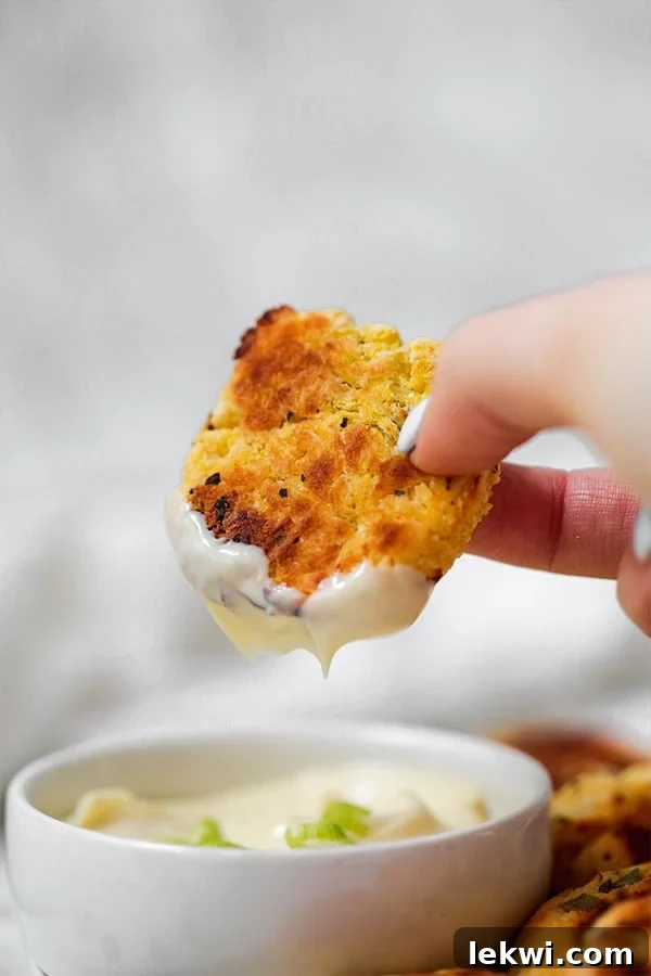 A hand holding a spaghetti squash nugget dipping into a white sauce.