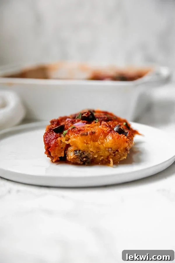 A close-up of spaghetti squash pizza casserole with visible strands of squash, meat, and vegetables.