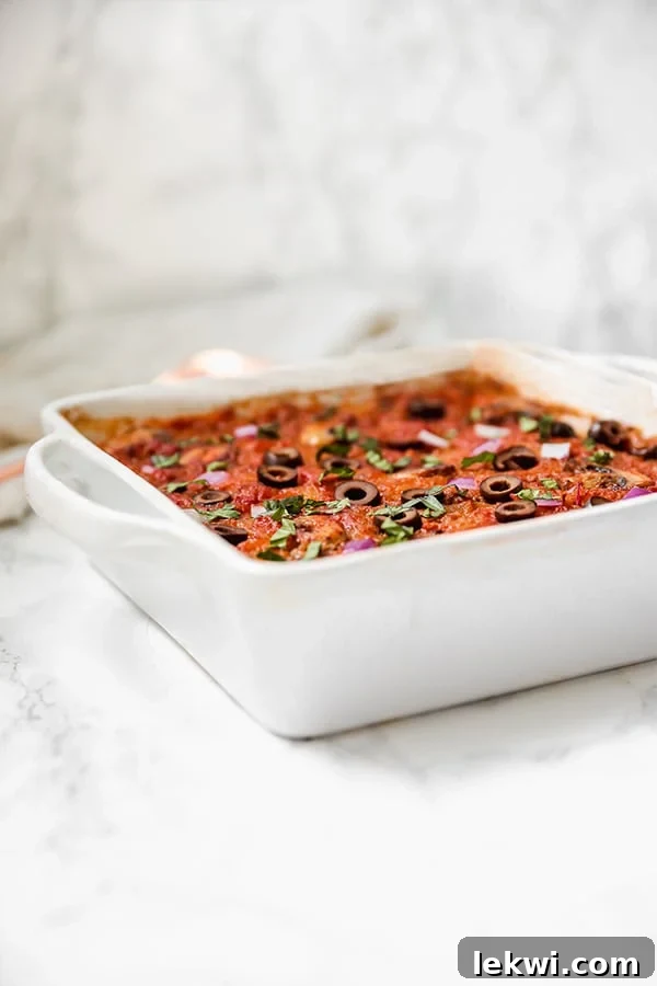 A close-up of a portion of spaghetti squash casserole in a dish, showing layers of squash, meat, and sauce.