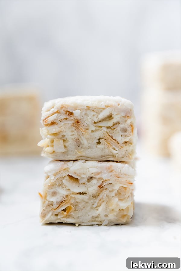 Two grain free "rice" crispy treats stacked on top of each other on a white background, highlighting their delightful texture.