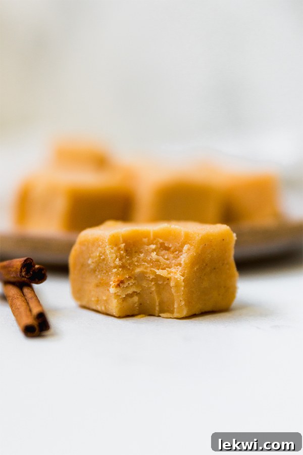 Delicious Paleo Pumpkin Fudge squares stacked on a white surface, garnished with cinnamon