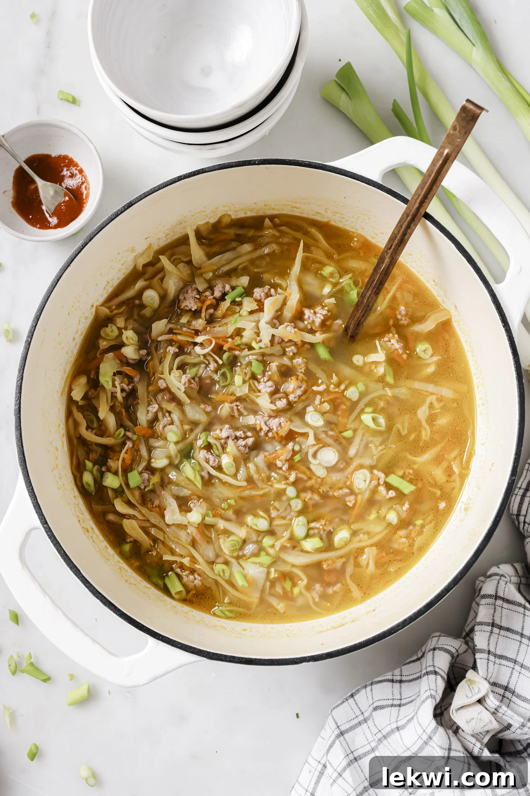 Egg roll soup in a large pot topped with green onions.