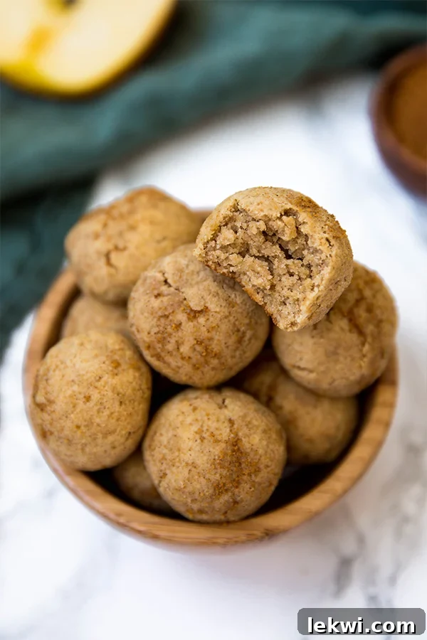 A hand reaching for a warm Paleo & AIP Apple Donut Hole from a wooden bowl
