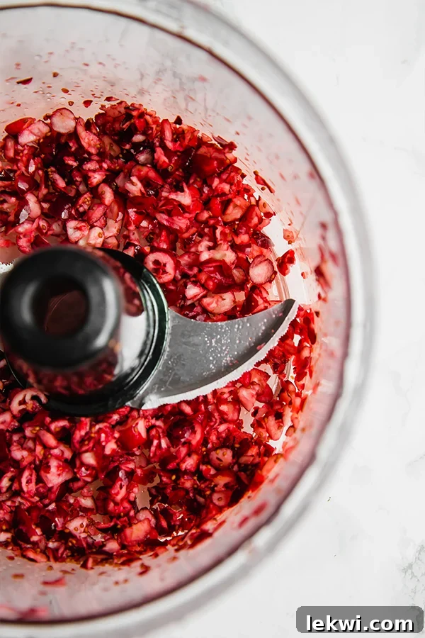 A food processor cutting up cranberries into pieces.