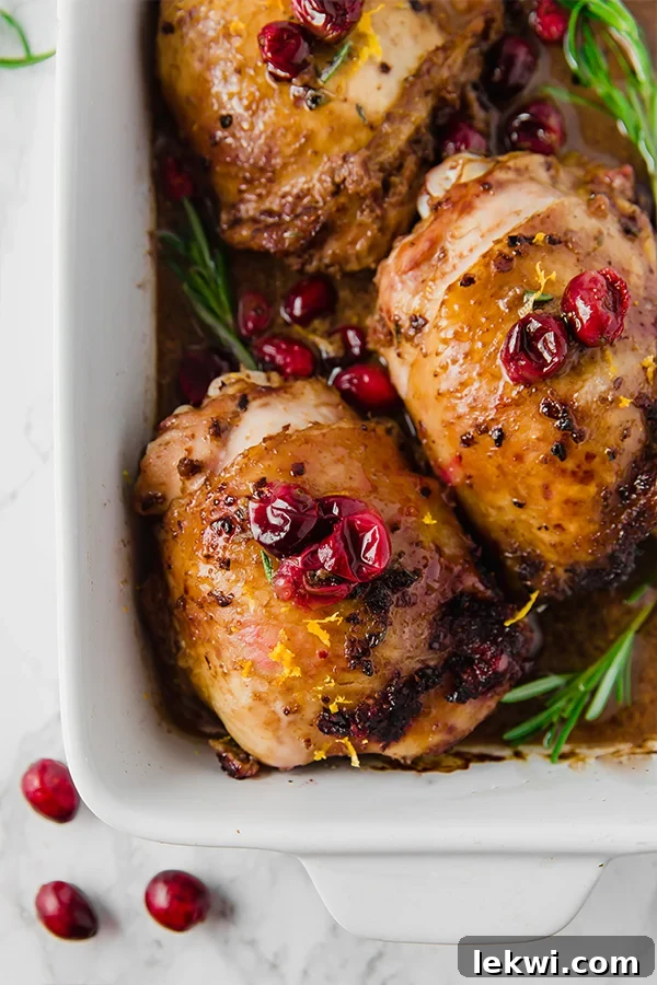 A white baking dish filled with orange cranberry balsamic chicken thighs after baking.