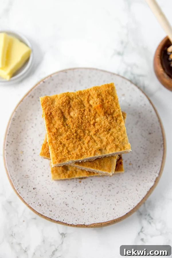 A grey plate with a stack of grain free cornbread squares stacked on it with butter nearby.