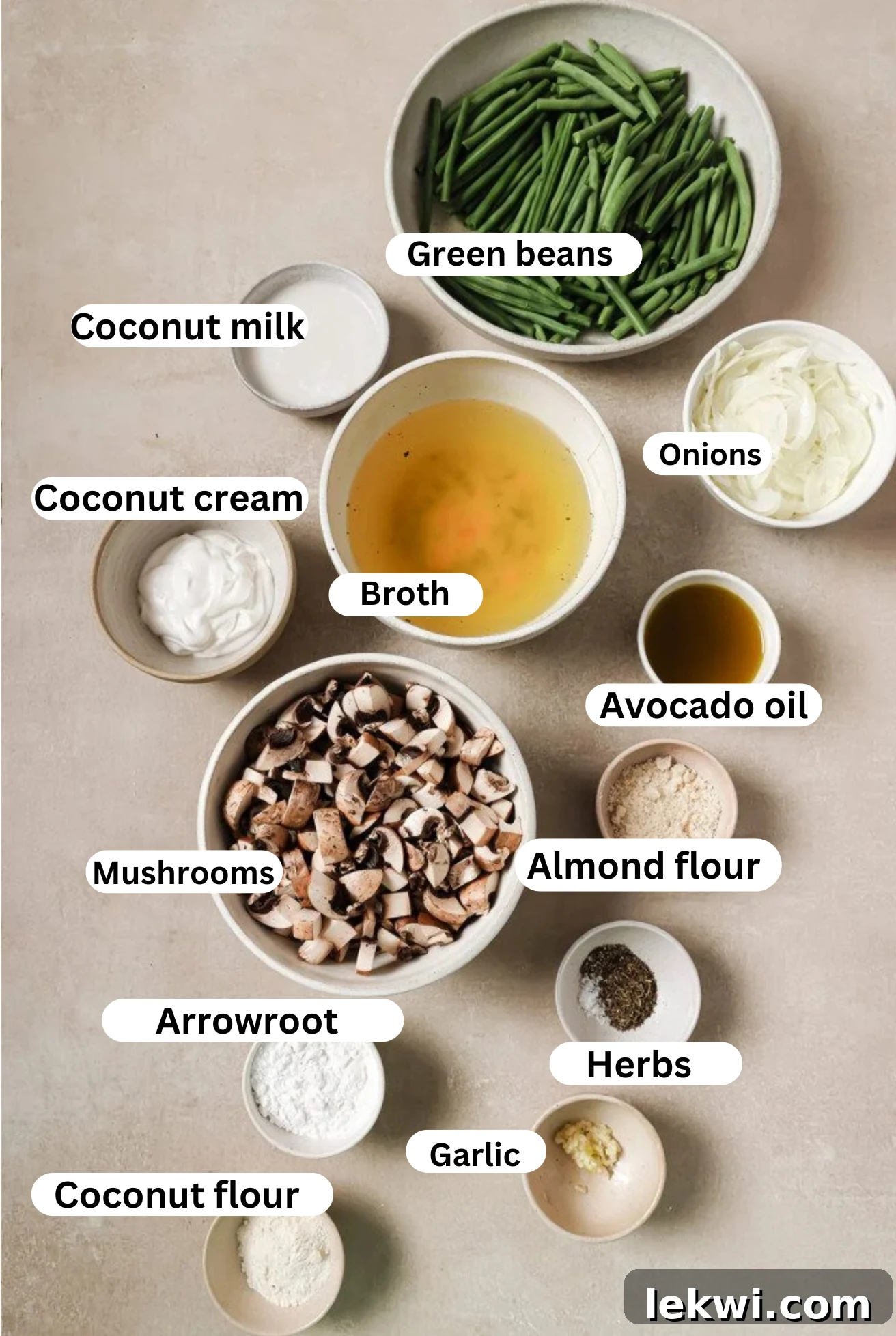 The ingredients for a homemade gluten-free green bean casserole laid out on a wooden surface, including fresh mushrooms, green beans, onions, and various flours and spices.