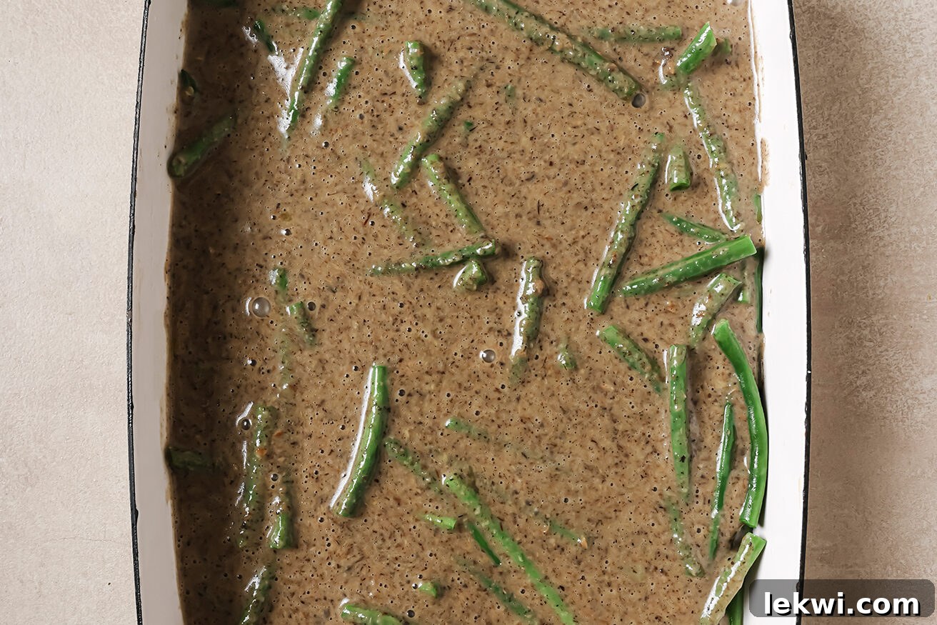 Green beans and mushroom soup mixed together in a casserole dish, ready for baking.
