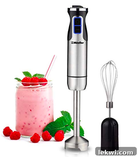 An immersion blender next to a glass with a perfectly blended pink beverage, showcasing its versatility.