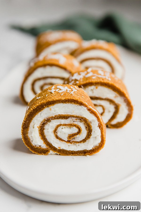 Several perfectly cut slices of homemade pumpkin roll cake, arranged invitingly on a white plate.