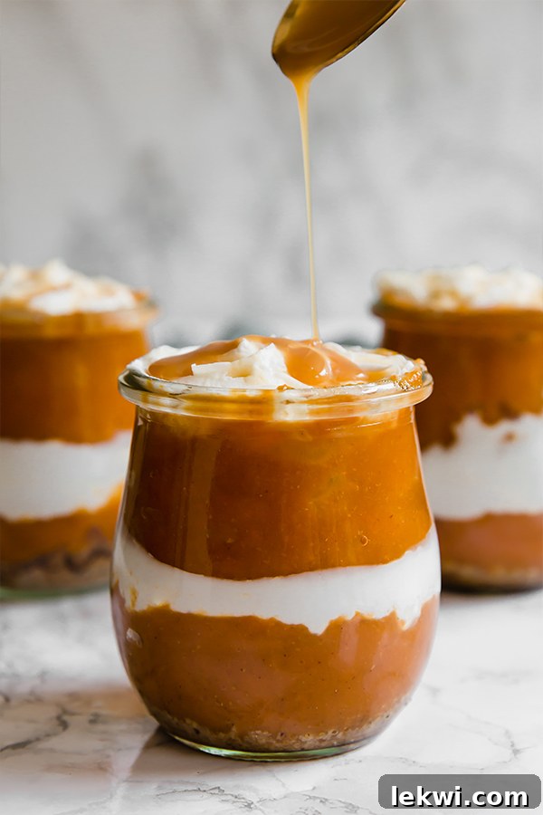 Three elegant glass jars filled with layered pumpkin parfaits, showcasing their delicious components.
