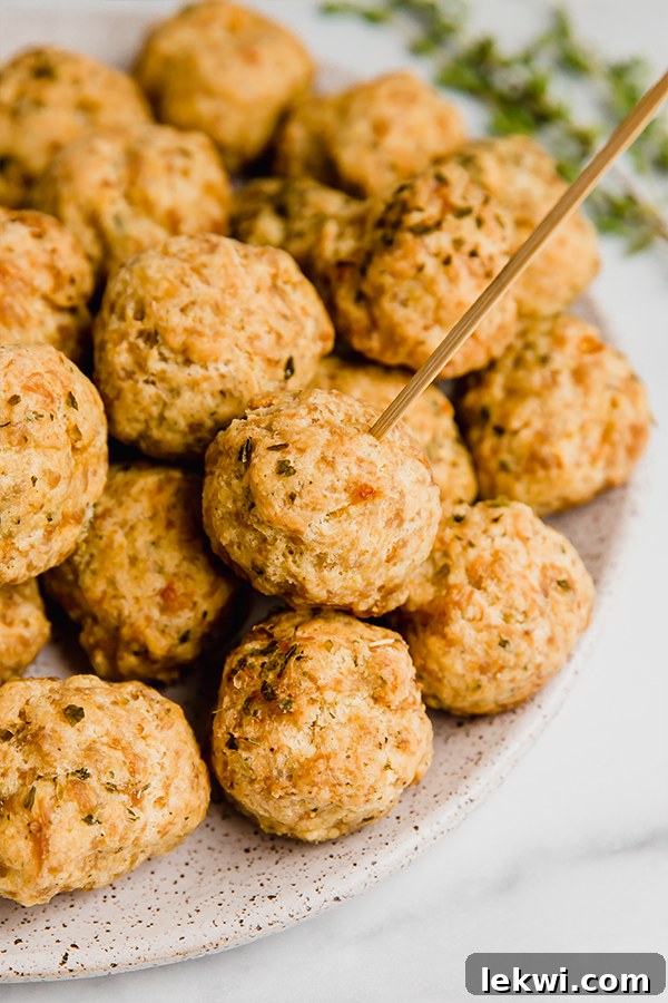 Delicious Paleo sausage balls arranged on a plate, with one pierced by a toothpick for easy serving.